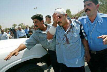 Un policía iraquí herido en la explosión es ayudado por dos compañeros a llegar a una ambulancia.