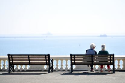 Una pareja de ancianos se sienta en un banco con vistas al mar en Plymouth, Inglaterra.