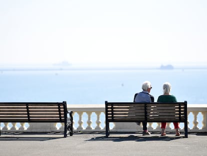 Una pareja de ancianos se sienta en un banco con vistas al mar en Plymouth, Inglaterra.