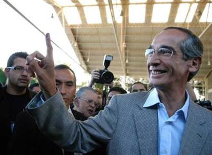 El candidato Álvaro Colom enseña el dedo con la marca de haber votado ayer en Guatemala.