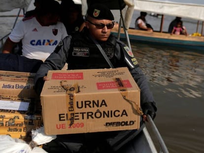 Policial carrega urna eletrônica no Rio Negro, em Manaus.