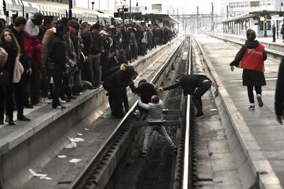 Várias pessoas ajudam uma mulher que caiu nas vias do trem de uma estação de Paris durante a greve ferroviária.