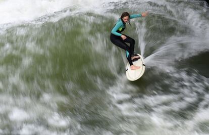 Una joven se encuentra haciendo surf en el canal de Eisbach, un sitio popular para los surfistas en el Jardín Inglés de Múnich, al sur de Alemania.