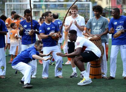 O inglês Danny Welbeck joga capoeira com um jovem na favela da Rocinha, no Rio.