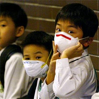 Dos niños se protegen con mascarillas en una escuela de Hong Kong.