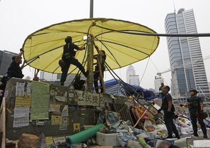 Oficiales de policía quitan un paraguas amarillo, símbolo del movimiento, que presidía una de las barricadas.