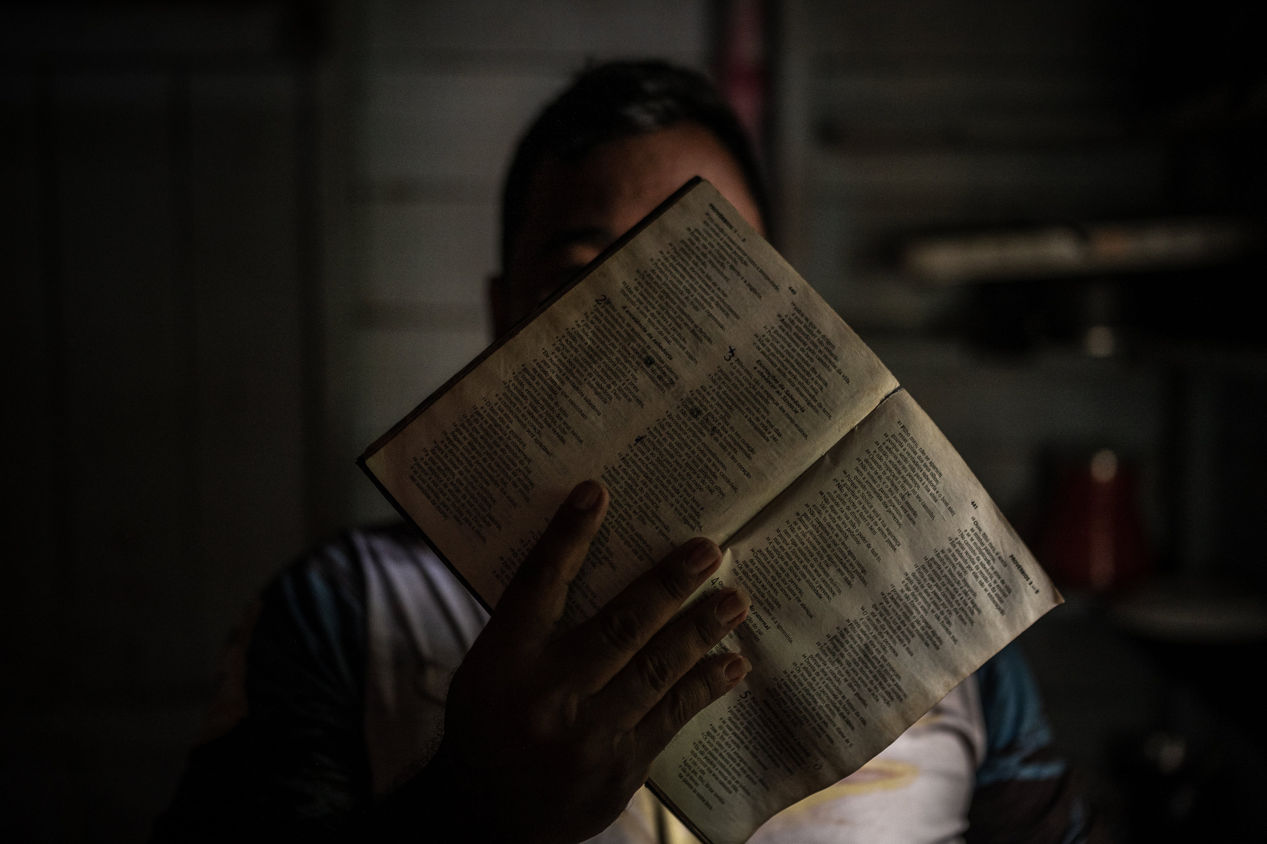 El pastor de una iglesia evangélica tapa su rostro con una biblia para proteger su identidad, en Benjamin Constant, en la Amazonía brasileña. 