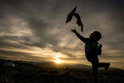 Un muchacho vuela su cometa al atardecer en un campamento improvisado para los migrantes y refugiados en la frontera de Macedonia, cerca de la aldea de Idomeni.