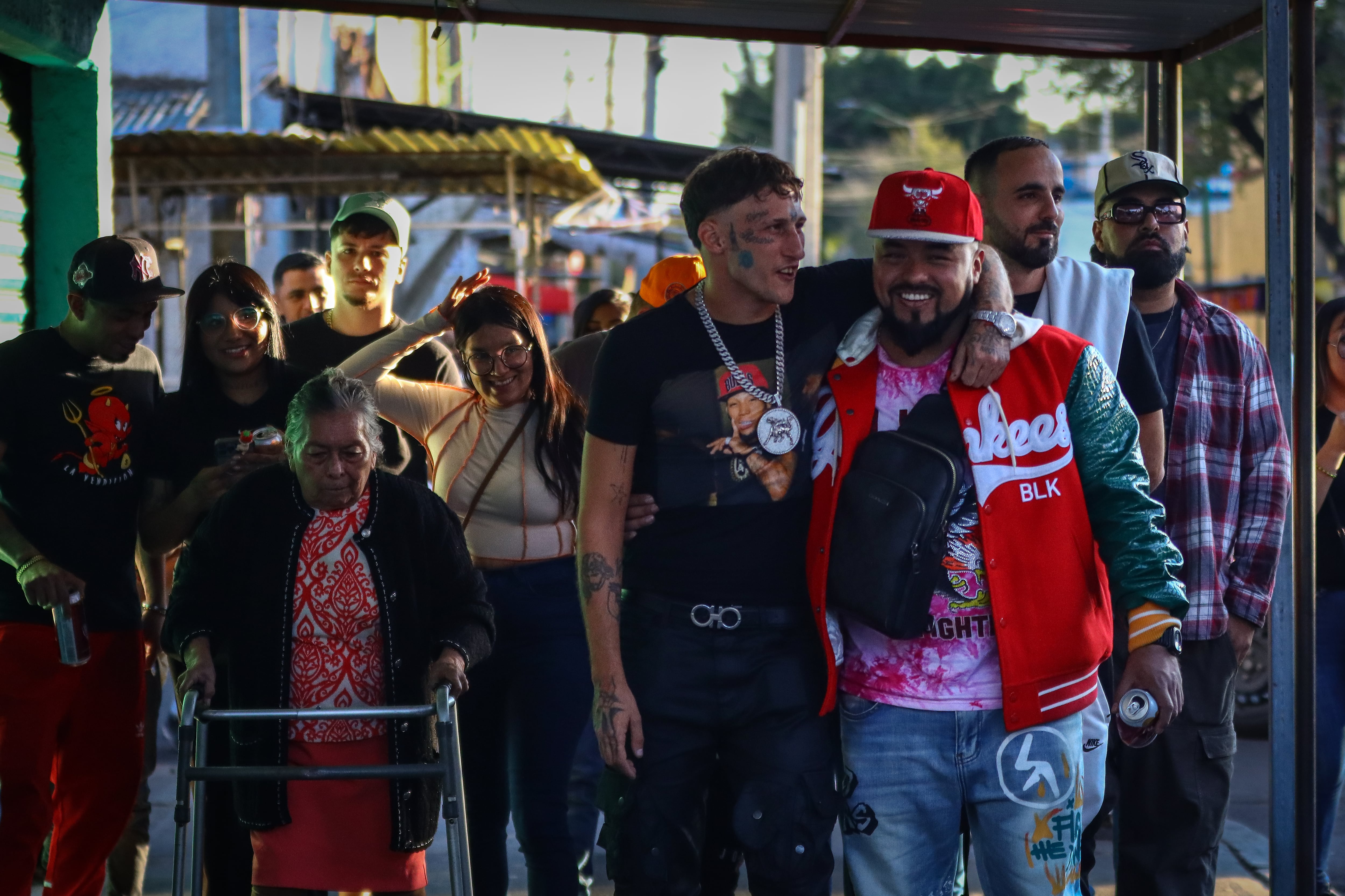 El rapero español camina con seguidores y su equipo en la calle que da entrada al altar del Angelito Negro, en el barrio de Tepito.