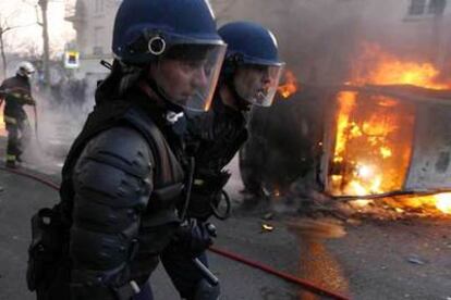 Policías antidisturbios franceses pasan ante un coche quemado, ayer tras la manifestación de París.