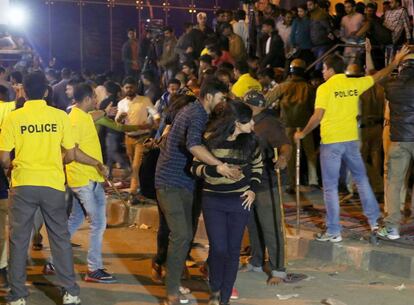 Un joven protege a una chica mientras la policía trata de controlar a la multitud en el festejo de Nochevieja en Bangalore.