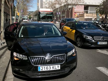 Un vehículo de Cabify recoge un pasajero al lado de un taxi, en Barcelona.