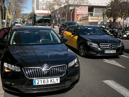 Un usuario de Cabify junto a un taxi, en Barcelona.