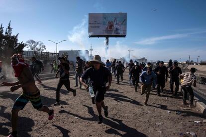 Decenas de migrantes huyen de los gases lacrimógenos.