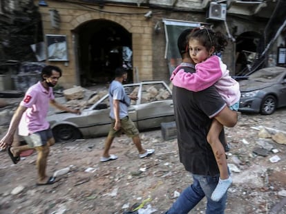 Un hombre lleva en brazos a una niña tras explosión del pasado martes en Beirut. 