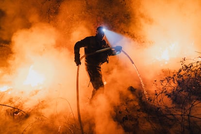 Un bombero utiliza una mangera para extinguir las llamas en el fuego forestal de Ribadavia (Ourense), este lunes.