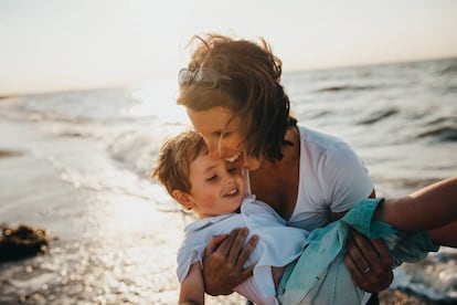 Una madre juega con su hijo en la orilla del mar.