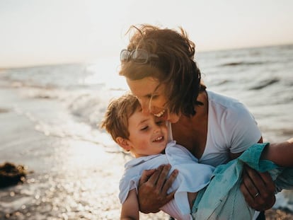 Una madre juega con su hijo en la orilla del mar.