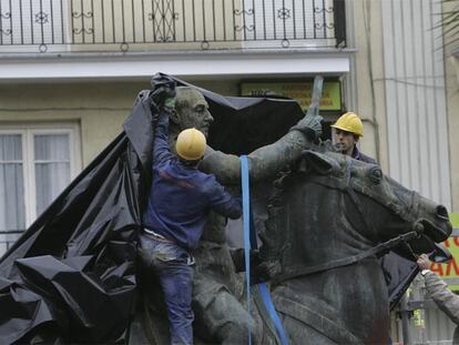 Tres operarios trabajan en la retirada de la estatua de Franco de Santander.