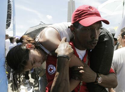 Un voluntario saca a una mujer que ha sufrido una lipotimia por las altas temperaturas que se registran en La Habana.