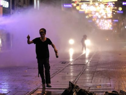 Un manifestantes corre ante los ca&ntilde;ones de agua de la polic&iacute;a este s&aacute;bado.