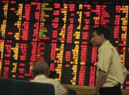 Inversores tailandeses permanecen ante las pantallas de datos bursátilesl en un mercado de valores privado de Bangkok (Tailandia). EFE/Archivo
