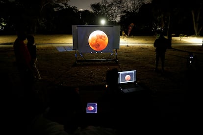 Varias personas observan el eclipse solar desde una pantalla instalad en el Planetario Humboldt en Caracas (Venezuela).  
