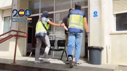 Dos agentes de la Policía Nacional trasladan a uno de los seis integrantes del grupo ultra Biris Norte detenidos como presuntos autores de una paliza a seguidores de un equipo rival, en una imagen del vídeo facilitado por el Ministerio del Interior.