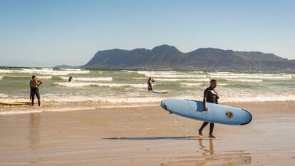 Yusuf y Atyab, dos surferos principiantes, salen del agua en la playa de Muizenberg, en Sudáfrica, el 12 de diciembre de 2020.