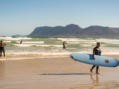 Yusuf y Atyab, dos surferos principiantes, salen del agua en la playa de Muizenberg, en Sudáfrica, el 12 de diciembre de 2020.