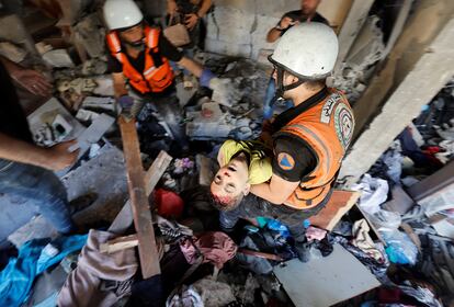 Trabajadores de emergencias rescatan a un niño palestino entre los escombros de una casa tras un bombardeo israelí, este viernes en Jan Yunis.