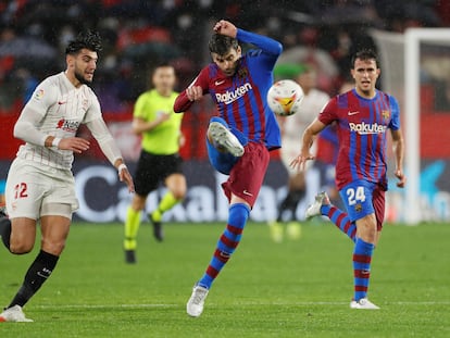 Piqué despeja el balón ante la presión de Rafa Mir durante el partido en el Pizjuán.