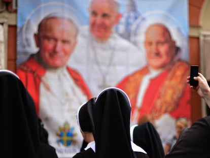 Varias monjas observan y fotografían un panel con la imagen de varios pontífices.