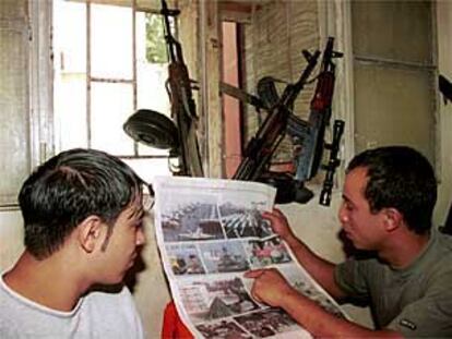 Dos jóvenes palestinos provistos de fusiles leen un periódico en un campo de refugiados del sur de Líbano.