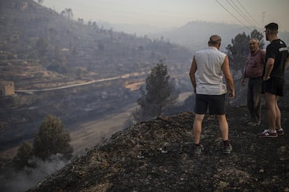 Habitantes de la zona recorren un paisaje quemado después por el incendio forestal en la Torre de l'Espanyol.
