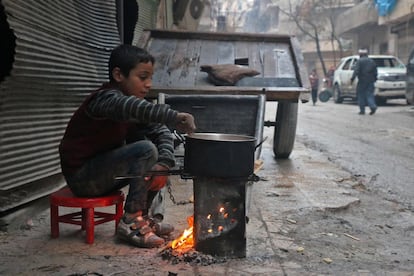 Menino cozinha em um bairro de Aleppo, em 13 de dezembro