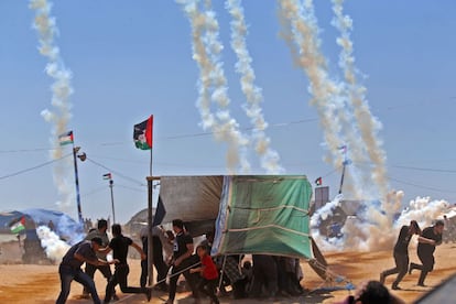 Um grupo de manifestantes palestinos se protegem do gás lacrimogêneo lançado pelas tropas israelenses na Faixa de Gaza.