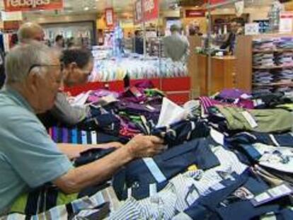 Varias personas rebuscan entre las prendas de un centro comercial de Madrid. EFE/Archivo