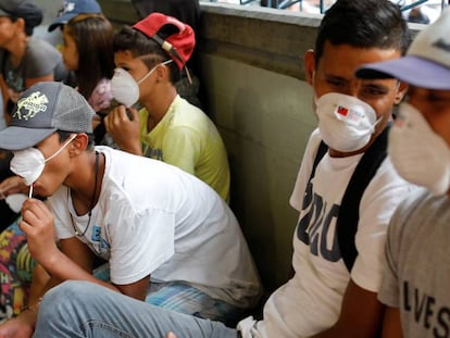 Gente con mascarillas cerca de una parada de metro en Caracas.