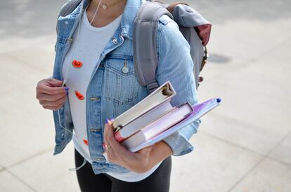 Una alumna universitaria carga material educativo de camino a su centro.