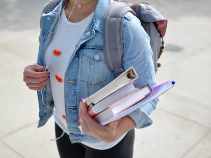 Una alumna universitaria carga material educativo de camino a su centro.