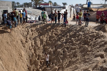 Civiles palestinos contemplan el boquete causado por una bomba en el campo de refugiados de Jan Yunís, en Gaza.