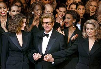 Yves Saint Laurent, escoltado por Laetitia Casta y Catherine Deneuve, ayer en París.