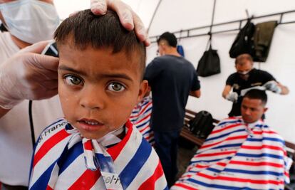 Migrantes venezolanos se cortan el pelo en la Brigada Social del gobierno local colombiano en Bogotá, el 27 de septiembre de 2018.