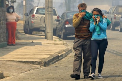 Un hombre y su hija cubren sus rostros al salir de su casa durante un incendio forestal en las laderas alrededor de Quito. Según el ministro del Interior, José Serrano, existe un plan de recompensas que ofrece 50.000 dólares a quien dé información útil para capturar a causantes de incendios.