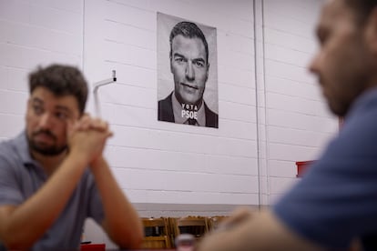 Daniel Valdivia (izquierda) y Juan Carlos Delgado, militantes del PSOE, en la sede del partido en Dos Hermanas (Sevilla), el miércoles de esta semana. Al fondo, un cartel del secretario general, Pedro Sánchez.