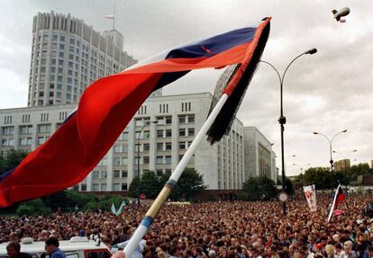 Uma bandeira russa é hasteada diante de uma multidão de cidadãos que participam dos funerais das vítimas do golpe em frente à Casa Branca de Moscou, em 24 de agosto de 1991.