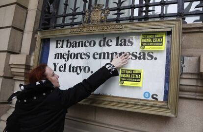 Una de las participantes en la manifestación contra los desahucios pega carteles contra los deshaucios en una entidad.