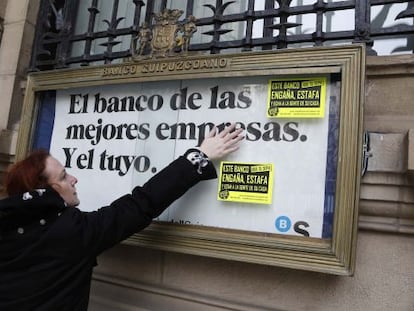 Una de las participantes en la manifestación contra los desahucios pega carteles contra los deshaucios en una entidad.