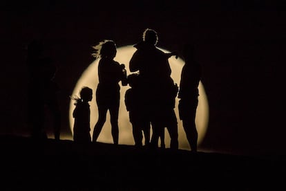 La gente mira la superluna elevándose en las dunas de arena en Lancelin (Australia).